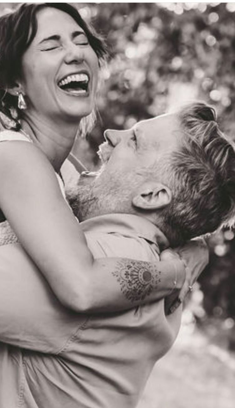 Black and white photo of Danielle laughing as Patrick holds her