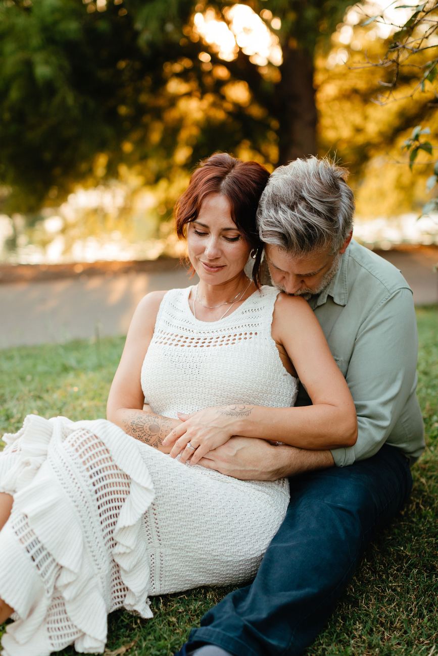 Danielle and Patrick sitting together under a tree at golden hour