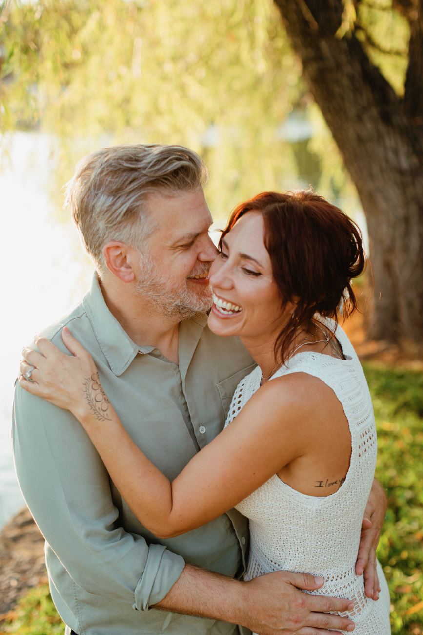 Danielle and Patrick embracing and laughing under a willow tree